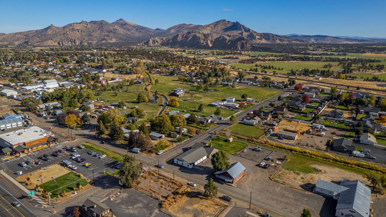 Wide Central Oregon aerial with Smith Rock on the horizon above nearby rooftops