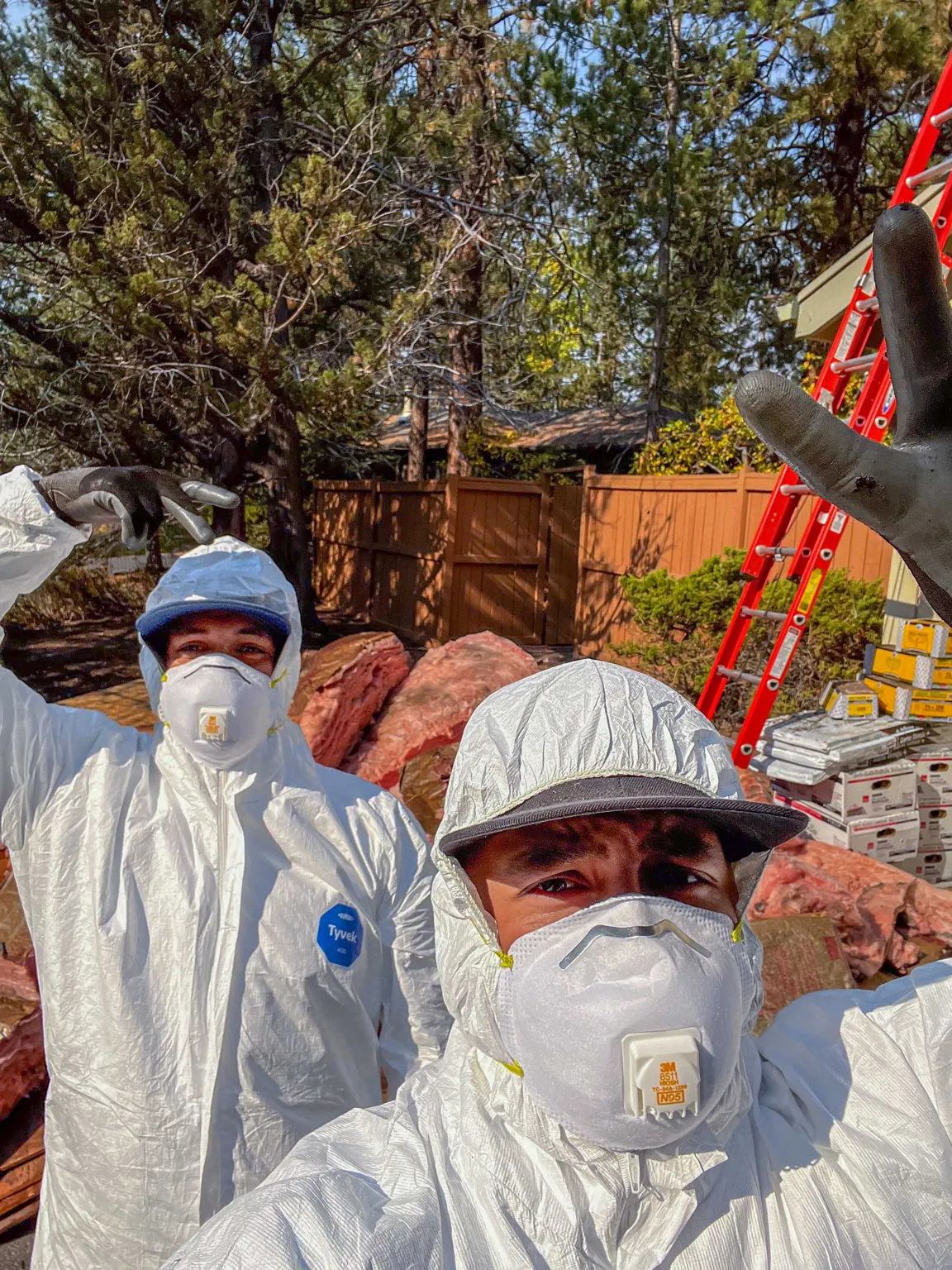 Two crew members in full protective suits and respirators before insulation removal