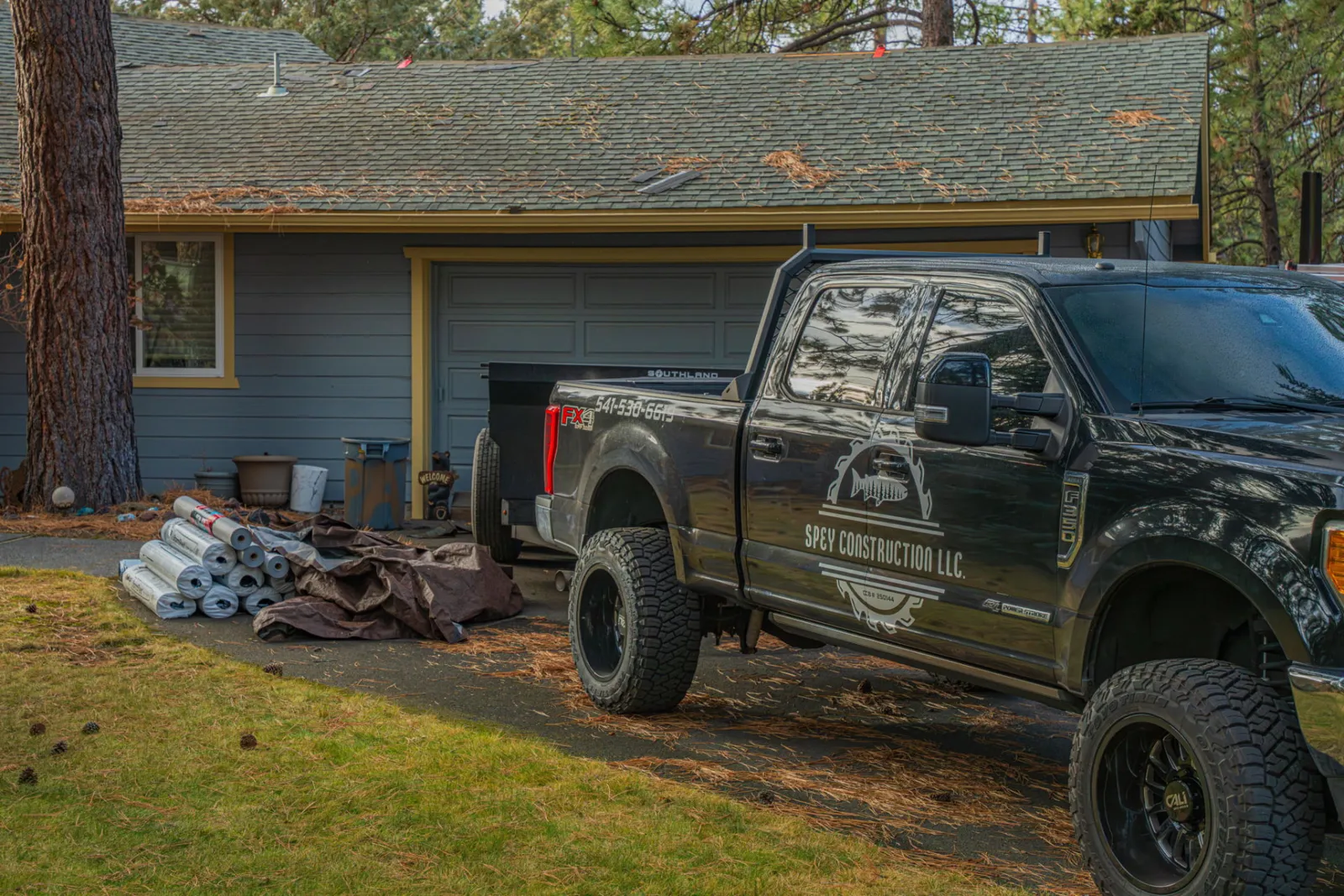 Spey Roofing truck staged at the jobsite with materials unloaded on the lawn