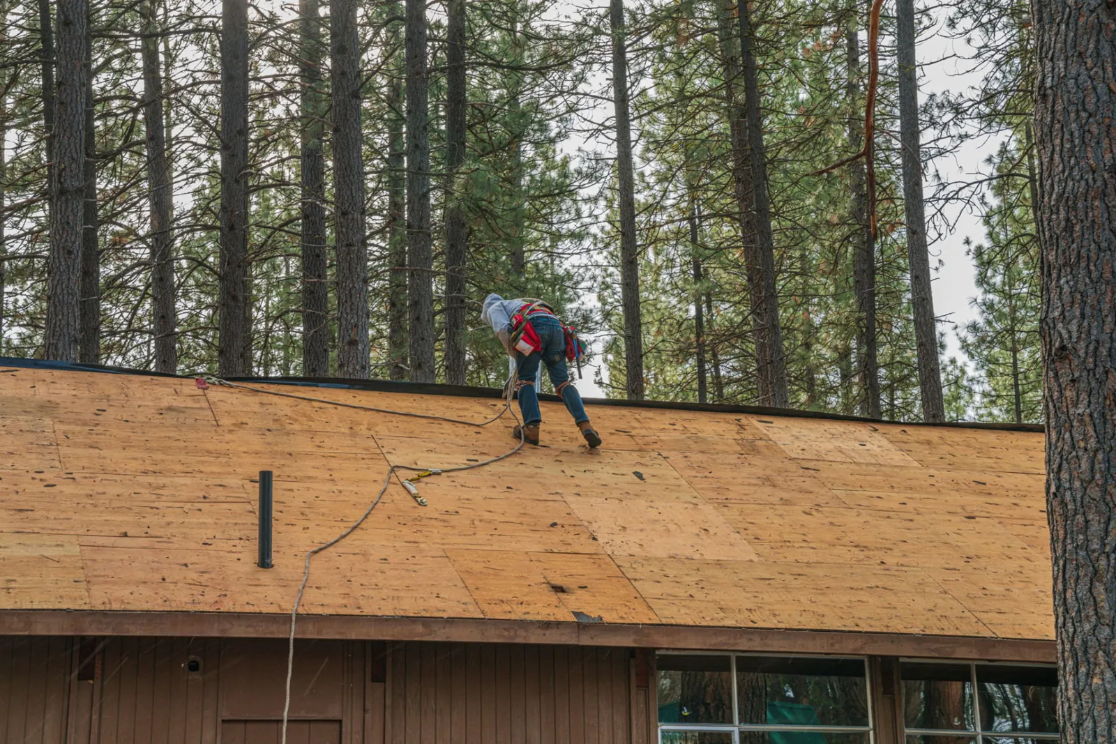 Roofer working across the bare wood deck during roof preparation