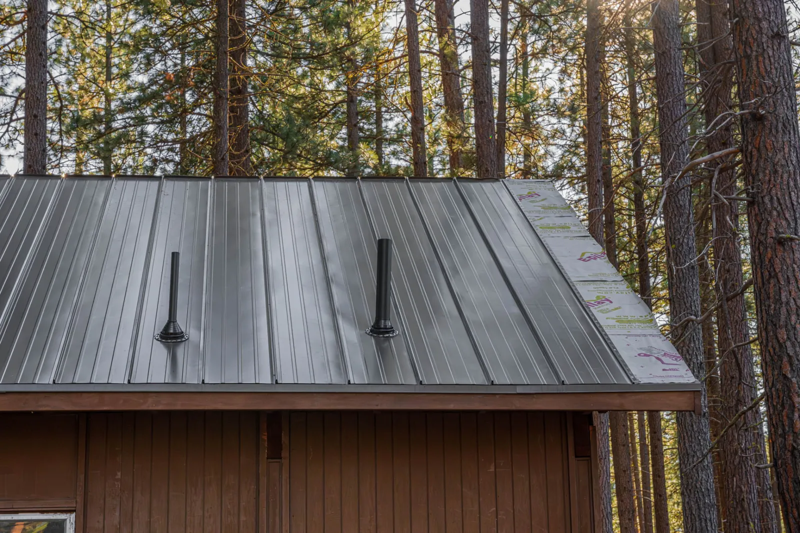 Standing seam metal roof on a cedar-sided home in the ponderosa pines