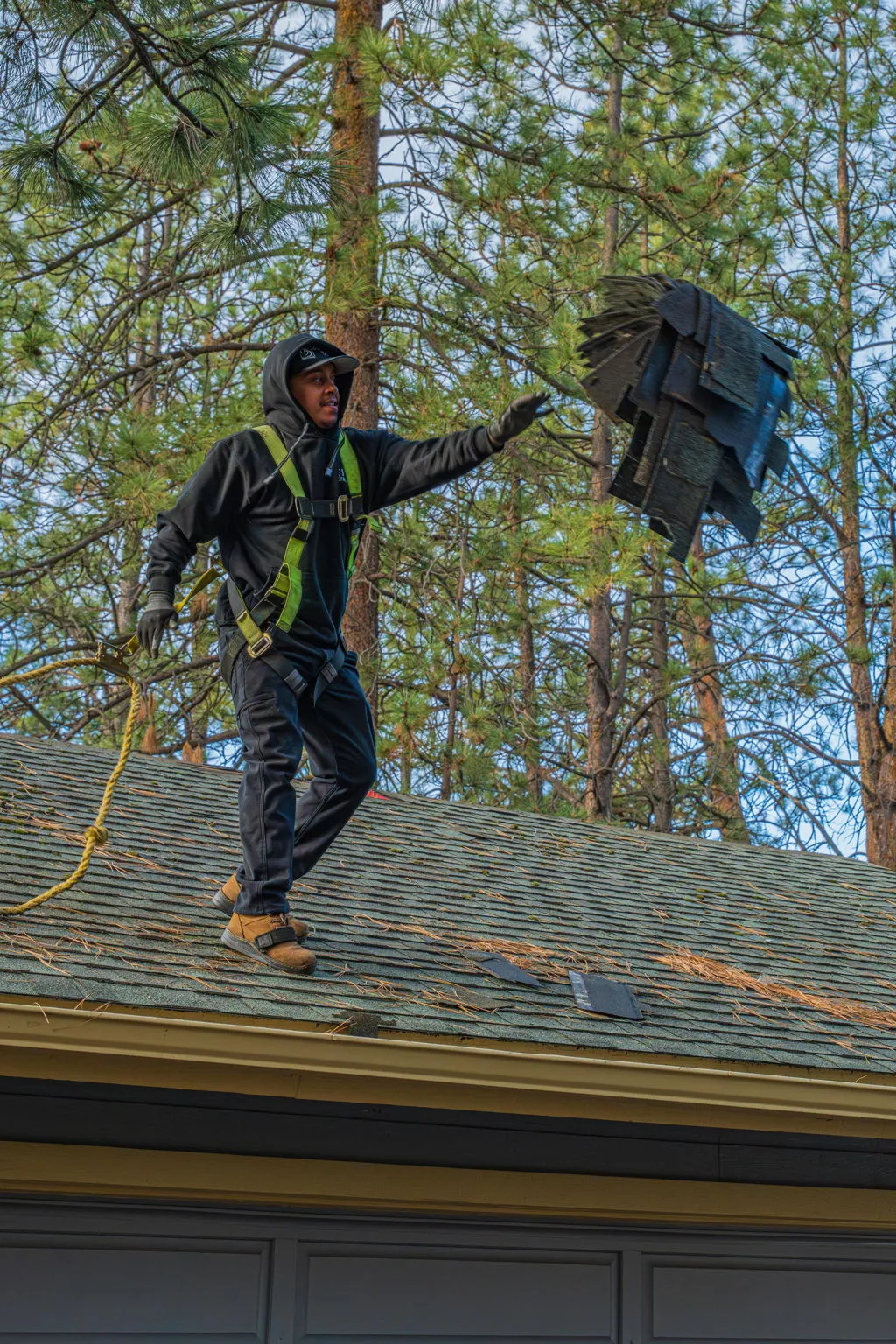 Spey Roofing crew member carrying a bundle of shingles across a roof in Bend, Oregon
