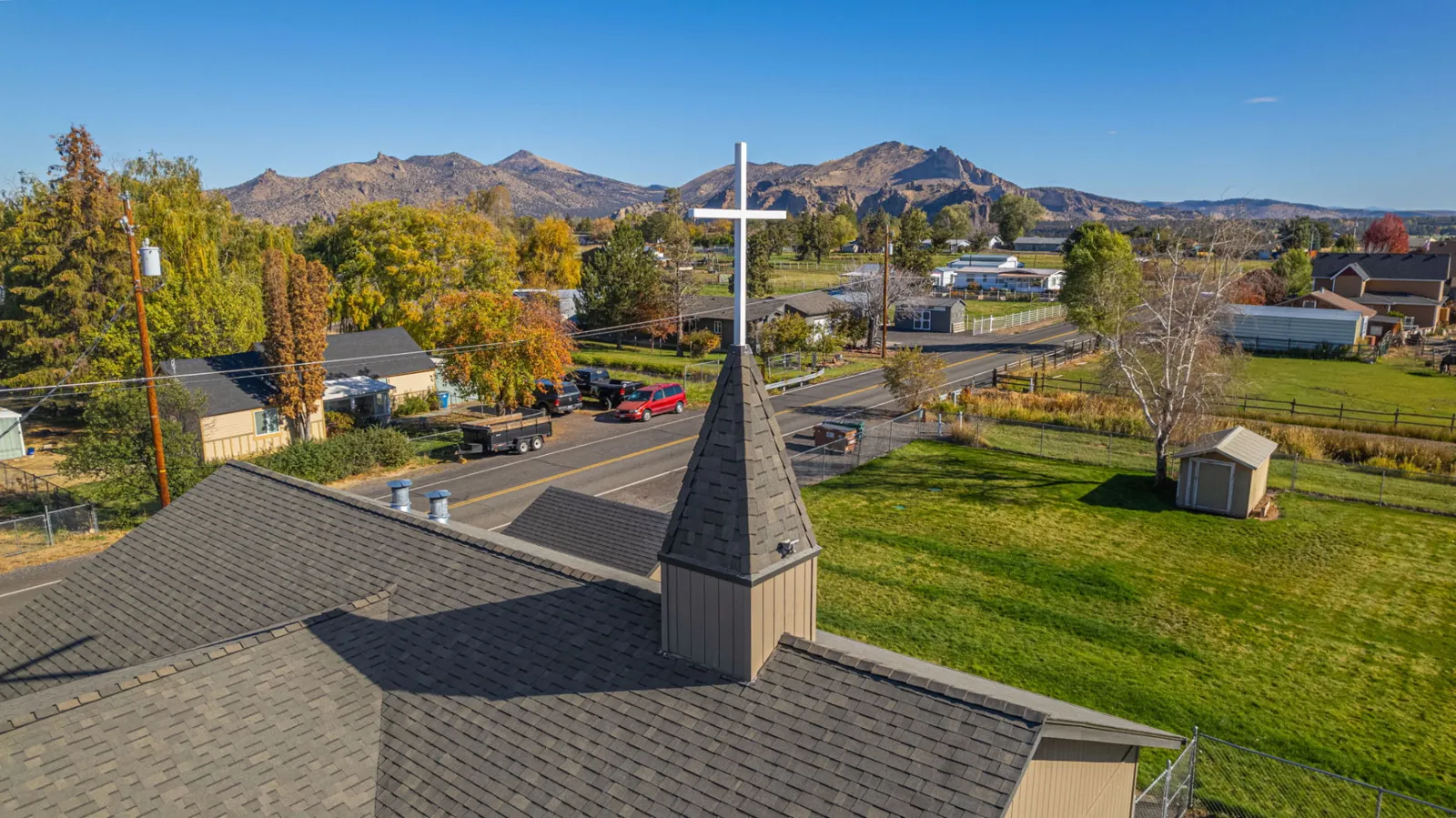 Steeple and cross rising above the finished church roof
